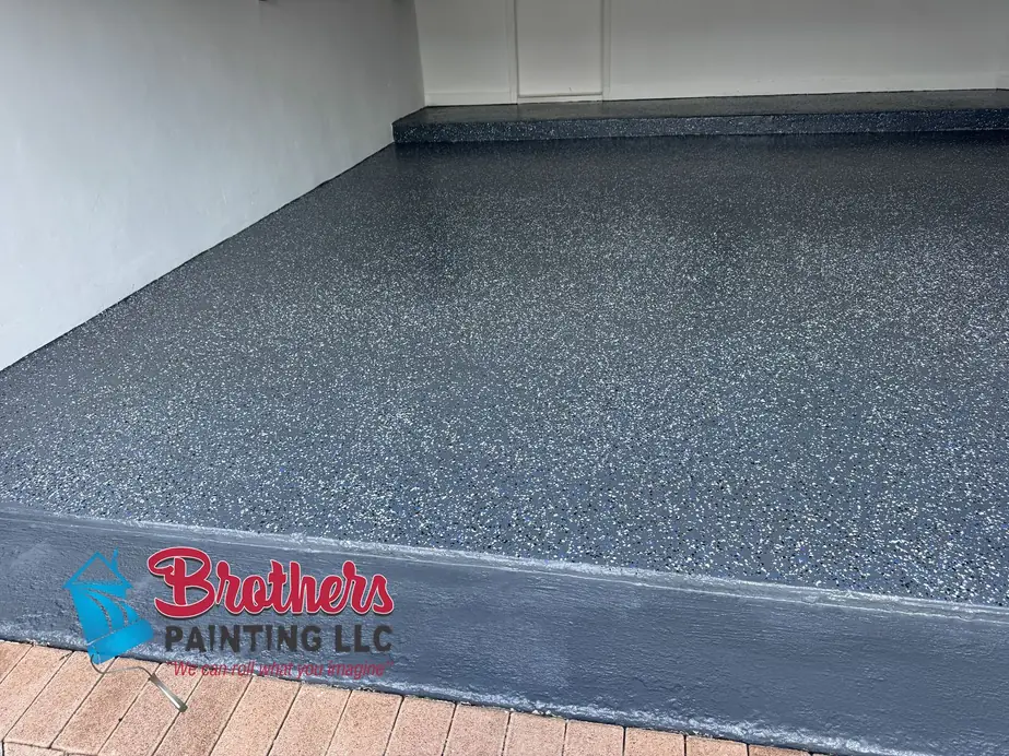 Close view of a charcoal-blue epoxy garage floor with decorative flake