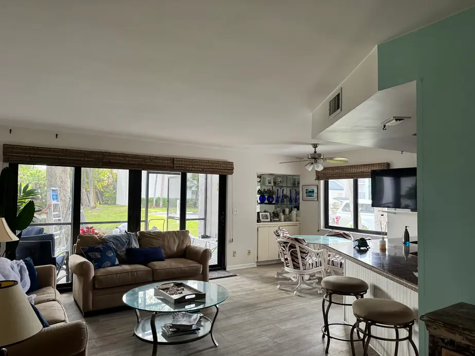 Lived-in living room with a seafoam accent wall and painters at work beyond the slider