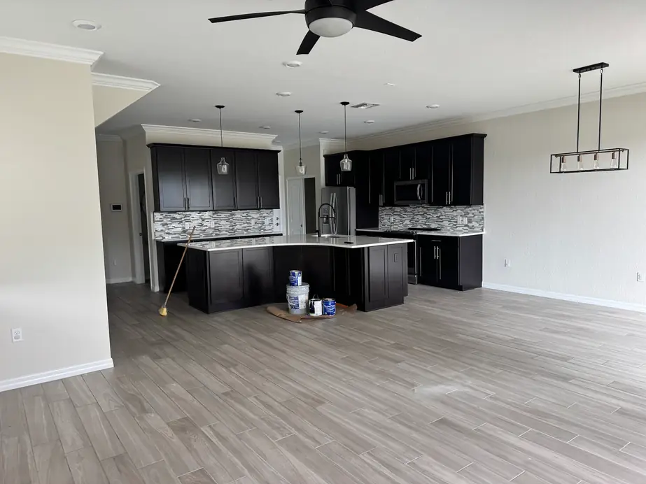 Open kitchen with dark cabinets and paint cans on the tile floor mid-job
