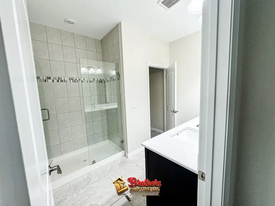 Bathroom with a navy vanity, glass shower and white doors and trim